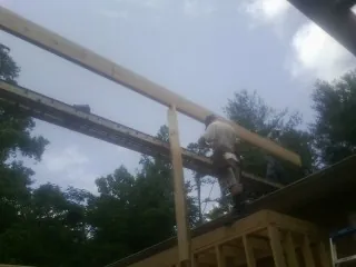 Carpenter setting a ridge beam over a new addition frame — Ice Dam Removal by Roofing Brothers in Saint Albans