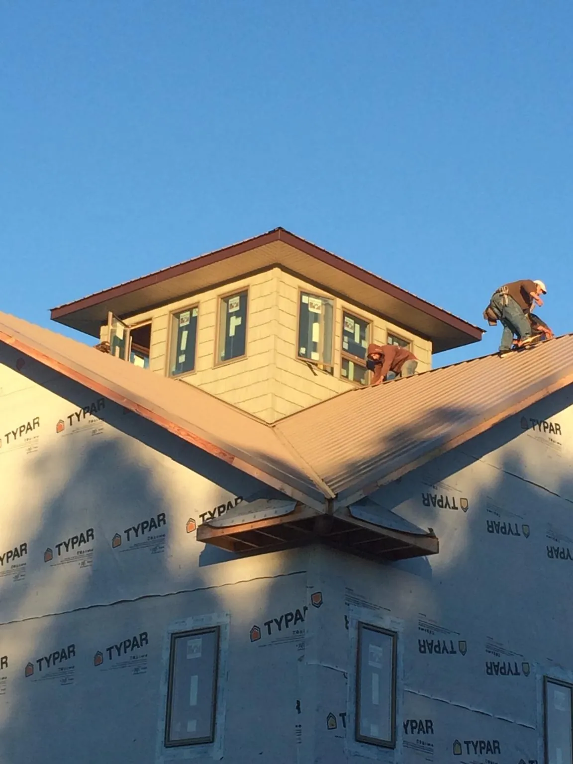 Roofers working around a rooftop cupola on a new metal roof at sunset — Roof Waterproofing in Saint Albans by Roofing Brothers